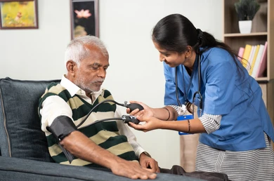 Nurse checking blood pressure of senior citizen at home